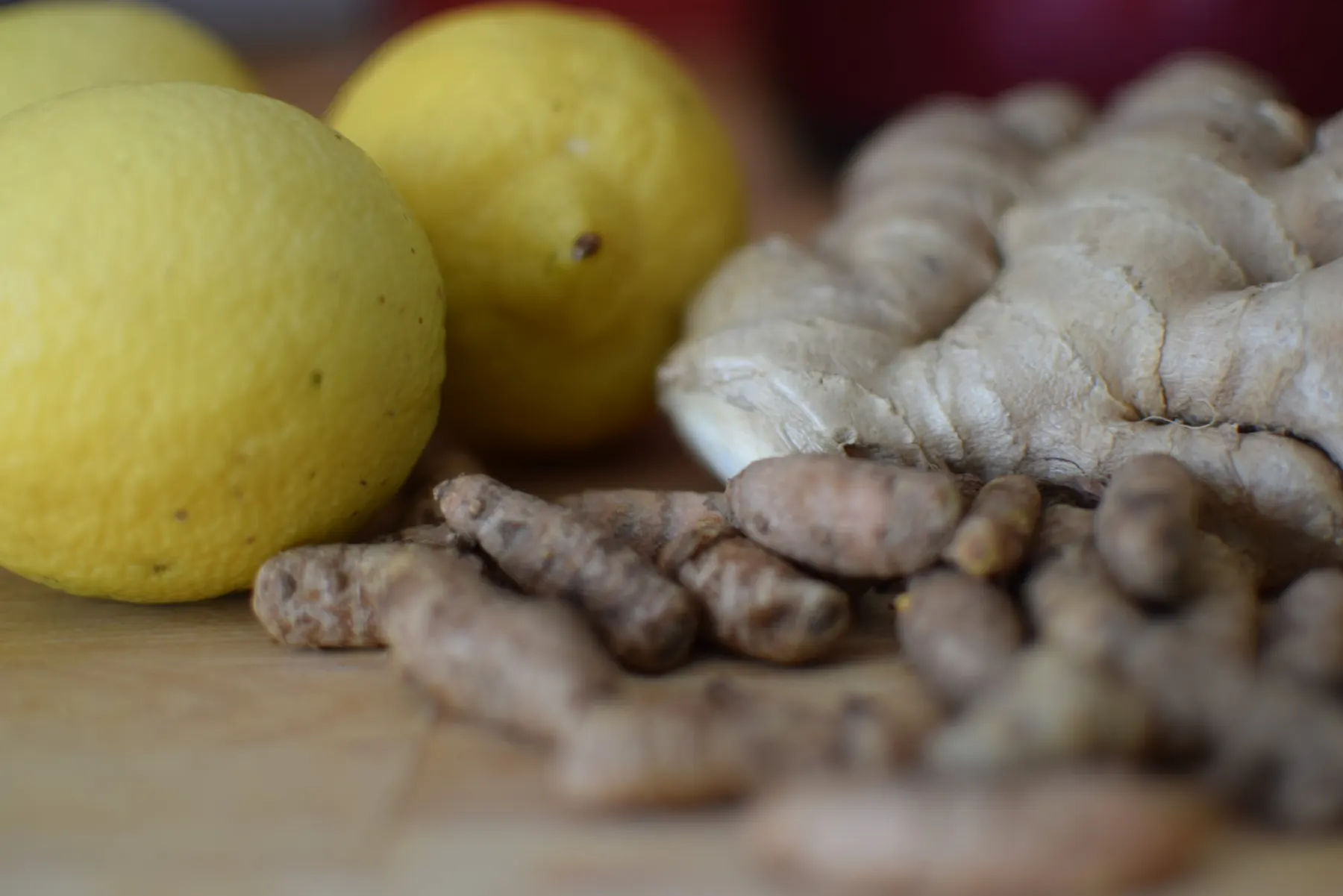 Ingrédients frais pour la recette du Pipi de dragon : citron, curcuma et gingembre sur une planche